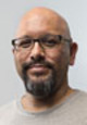 G. Neri author photo showing him wearing glasses with a beard and a heather gray t-shirt.